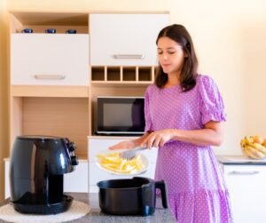 Airfryer preparando alimentos na cozinha com destaque para economia de energia e consumo mensal de eletricidade.